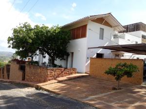 a white house with a stone wall and a tree at Hotel Alto Del Viento in Barichara