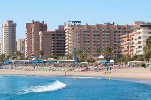 a beach with people in the water and buildings at Gran apartamento céntrico y muy cerca de la playa in Fuengirola