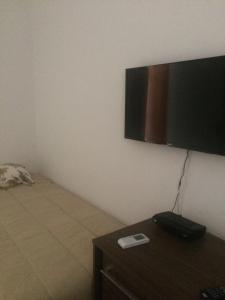 a room with a tv on the wall and a table at Hospedaria Nossa Casa in Braço do Norte