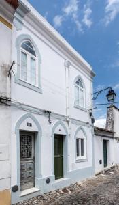 uma casa branca com uma porta verde e janelas em Casa dos Apóstolos em Évora