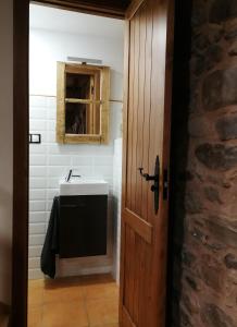 a bathroom with a sink and a wooden door at Casa Blanquita in Molinaseca