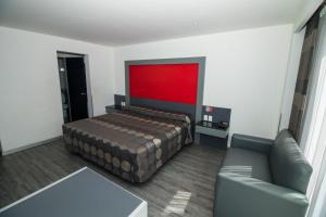 a bedroom with a bed and a couch and a red wall at Hotel Atenas Plaza in Mexico City