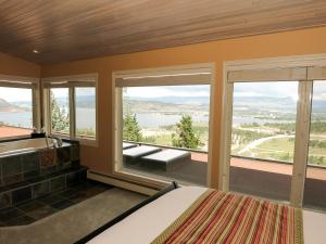 Schlafzimmer mit einem Bett, einer Badewanne und Fenstern in der Unterkunft A View of the Lake B & B in West Kelowna