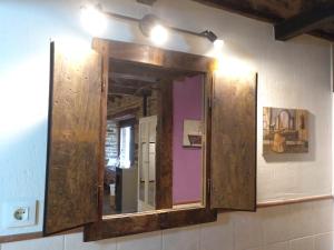 espejo de baño con marco de madera en la pared en CASA RURAL Calma del Lago, en Triufé