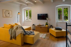 a living room with yellow furniture and a flat screen tv at Casa Bel Olivo in Vodnjan