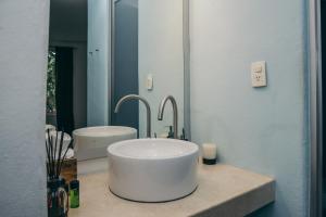 baño con lavabo blanco grande y espejo en Teetotum hotel, en Tulum