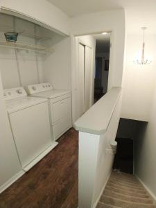 Una cocina blanca con lavadora y secadora. en Exclusive Townhome - Central Raleigh Location, en Raleigh