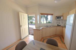 a kitchen with a table and a white refrigerator at Lakeview Apartments in Kununurra