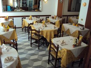 un ristorante con tavoli e sedie bianchi e uno specchio di Hotel La Salsesina a Salsomaggiore Terme