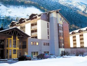 un edificio con coches aparcados frente a él en la nieve en Lagrange Vacances Cybèle en Brides-les-Bains