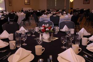 a room filled with tables with white tablecloths and chairs at Yuma Inn & Suites in Yuma