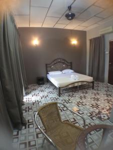 a bedroom with a bed and chairs on a tiled floor at Hana Guesthouse in Kuala Tahan