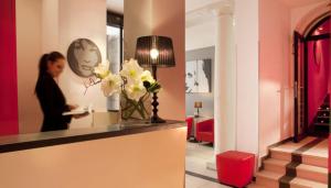 a woman in a hotel lobby with a vase of flowers at Villathena in Paris