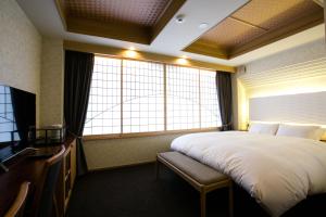 um quarto de hotel com uma cama grande e janelas em Kyoto Kamanza Hotel em Quioto
