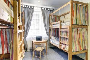 a room with bunk beds and a desk with a laptop at Hostel Uralskie Berega in Yekaterinburg