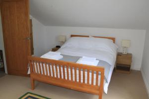 1 dormitorio con 1 cama con sábanas blancas y 2 mesitas de noche en The Dartmoor Linhay en Yelverton