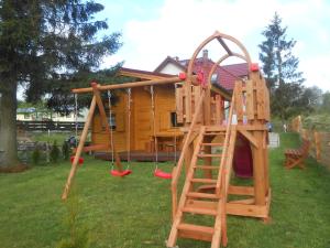 a wooden playground with a ladder and a house at Domek pod Świerkiem in Wapnica