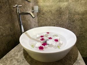 eine weiße Schüssel mit Blumen im Waschbecken in der Unterkunft Mount shadows in Ella