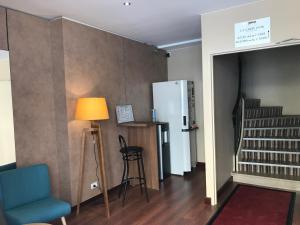 a living room with a blue chair and a refrigerator at La Carpe d'Or in Fontainebleau