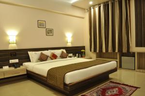 a bedroom with a large bed and a television at Hotel K Square in Kolhapur