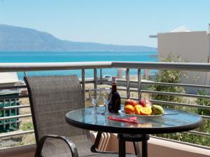 a table with a bottle of wine and fruit on a balcony at Pearl kokkonaki in Kokóni