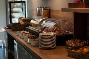 ein Buffet mit Tellern und Speisen auf der Theke in der Unterkunft Lagrange Aparthotel Montpellier Millénaire in Montpellier