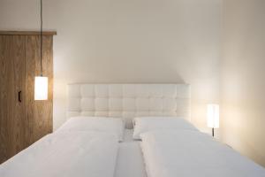 Biała sypialnia z 2 białymi łóżkami i 2 światłami w obiekcie Weingut Weidlhof - Suite & Breakfast - Vacation for wine lovers w mieście Caldaro +37 zdjęć