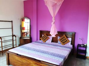 ein Schlafzimmer mit einem Bett mit einer lila Wand in der Unterkunft Saga Home in Ambalangoda