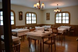 un restaurante con mesas y sillas blancas y ventanas en Puerta del Sol en Ciudad Rodrigo