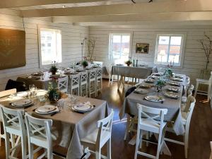 a room with long tables and white chairs at Vindängs Gård Hagbards By in Slöinge