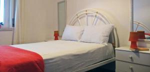 a bedroom with a white bed with a red blanket at Nazare with Garden and Barbecue in Nazaré