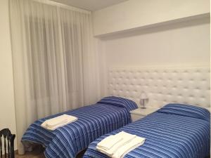 two beds in a room with blue and white sheets at Itaka in LʼAquila