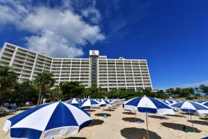 a row of blue and white umbrellas on a beach at Renaissance Okinawa Resort in Onna