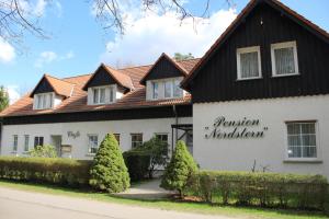 dom z czarnym dachem w obiekcie Pension & Restaurant Nordstern w mieście Chociebuż