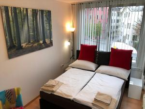 Bett mit roten Kissen in einem Zimmer mit Fenster in der Unterkunft Apartment Maximilian in old Town in Innsbruck