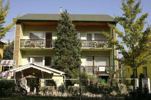 Casa amarilla con balcón y árbol en Oleander Apartman, en Hévíz