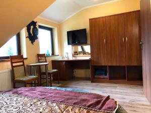 a bedroom with a bed and a desk and a tv at Gościnny Dworek in Pobierowo