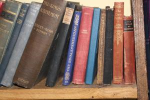 a row of books sitting on a shelf at The Old Apple Shed cosy heated cottage in a meadow close to the charming village of Bethersden in Ashford