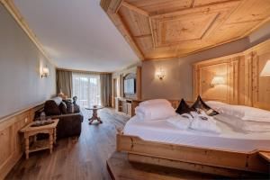 a bedroom with a large bed with a wooden ceiling at Quellenhof Luxury Resort Passeier in San Martino +97 photos
