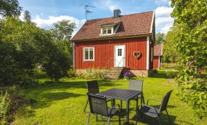 una mesa y sillas frente a una casa roja en Bosgårdens Cottages, en Broddetorp