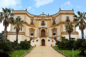 an old building with palm trees in front of it at Gli Artisti Apartments & Rooms in Bagheria