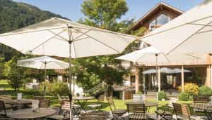 grupa stołów i parasoli przed budynkiem w obiekcie Felbermayer Hotel & AlpineSpa-Montafon w mieście Gaschurn