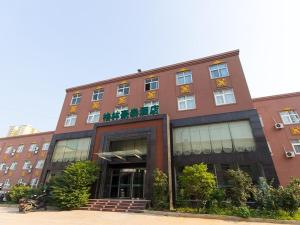 a large brick building with windows and plants at GreenTree Inn Henan Zhengzhou Chengnan Road Bojue Business Hotel in Zhengzhou
