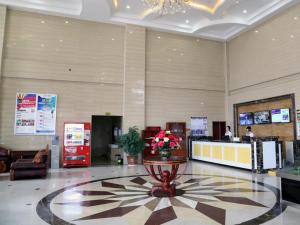 a lobby of a hotel with a reception desk and flowers at GreenTree Inn Shandong Zaozhuang Shanting JinkeGuoji Yijiaren Business Hotel in Zaozhuang