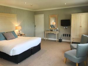 um quarto de hotel com uma cama grande e uma cadeira em Netherwood Hotel & Spa em Grange Over Sands