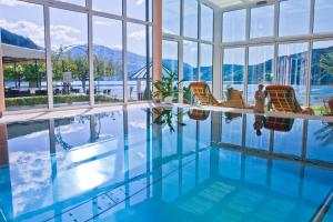 a swimming pool with chairs and a view of the mountains at SEEGLÜCK Hotel Forelle Superior in Millstatt