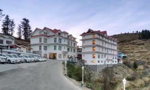 a group of buildings on a hill with parked cars at Hotel The Twin Towers in Shimla