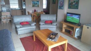 a living room with a couch and a tv and a table at La Palma Villas in Mossel Bay +8 photos