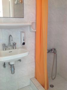 Baño con cortina de ducha naranja junto a un lavabo en ELEFTHERIA rooms, en Livadion