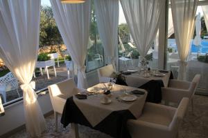 una sala da pranzo con 2 tavoli e tende bianche di Relais Lali' a Mottola
